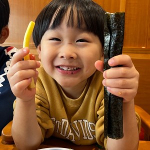 大好きなお寿司屋さんでポテトと海苔巻きを手にして幸せな顔