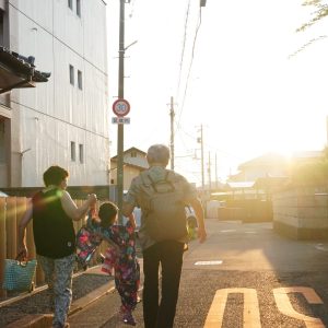 祖父母と孫が手を繋ぎ、花火大会へ向かう後ろ姿を撮影しました。
夕暮れの光のなかで、これから始まる時間に胸を弾ませながら歩く姿に、重ねてきた時間とこれからも続いていく時間を重ねました。